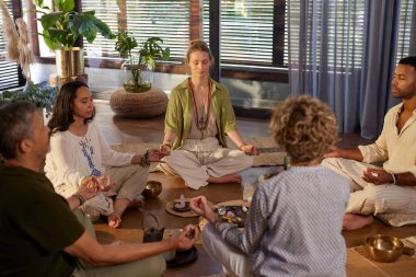 Bir grup ruhani insan bir çemberin içinde birlikte meditasyon yapıyor. Bir grup farklı insan birlikte meditasyon yapıyorlar. Ruhsal sağlık inzivasında, bağlantı ve kristal iyileşme. Çemberde oturan farklı bireyler, farkındalık çalışırlar.