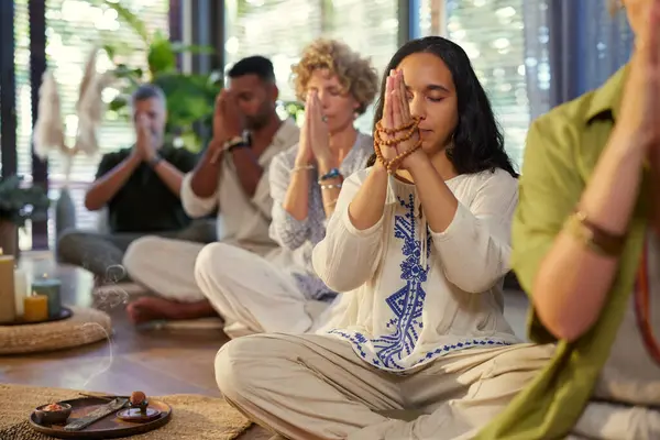 Çeşitli gruplar gözleri kapalı meditasyon yapıyor ve dua eden eller, yanan tütsüyle sağIık inzivasına çekiliyor. Latin Latin bir kadın şükran anında dua etmek ve meditasyon için mala boncukları tutuyor. İçerideki sakinlikte ruhsal bir bağlantı.