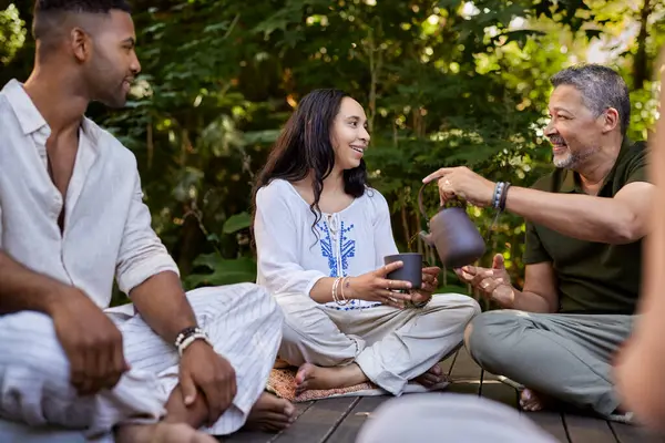 Bir grup yetişkin, huzurlu bir orman ortamında bir fincan çayı paylaşıyor. Bağlantının ve rahatlamanın keyfini çıkarıyorlar. Orta yaşlı bir adam holistik rehabilitasyon merkezinde gülümseyen melez bir kadın için çay dolduruyor. Karışık ırktan insanlar doğada rahatlar, eğlenirler.