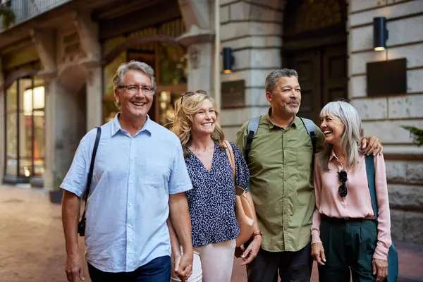 Hafta sonu bir gezi sırasında gülümseyen ve konuşan iki olgun çift. Mutlu yaşlı erkekler ve gülümseyen güzel kadınlar kasabada yürüyüş yapmaktan hoşlanırlar. Bir grup çok ırklı son sınıf öğrencisi, bir gezi sırasında el ele yürüyorlar ve dışarıda gülüyorlar..