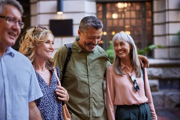 Bir grup eski dost dışarıda gülümsüyor ve birlikte yürüyorlar. Mutlu yaşlı çiftler şehirde eğleniyor. Dört yetişkin erkek ve kadın şehir sokaklarında yürürken konuşuyor ve gülüyorlar..
