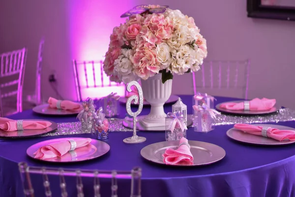 Düğün resepsiyonu için çok güzel bir masa. Akşam yemeği için bir mum ve mor süslemeler.