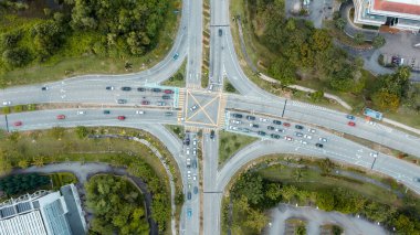 Trafik kavşakları, modern şehir. Malezya 'daki yoğun yol kavşağına yukarıdan bak. Renkli arabalar ve kamyonlar her iki yönde de karşıya geçiyor. Yol ayrımının havadan görüntüsü