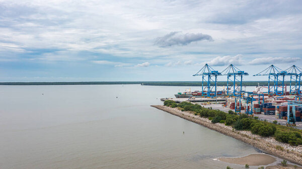 Klang, Malaysia - October 09, 2022: Cranes at the port Klang near Kuala Lumpur. Container crane at Klang Harbor. Aerial view on a container ship which is being loaded. Heavy Trucks at the Cargo bay