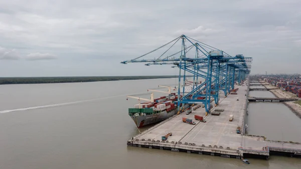 stock image Klang, Malaysia - October 09, 2022: Cranes at the port Klang near Kuala Lumpur. Container crane at Klang Harbor. Aerial view on a container ship which is being loaded. Heavy Trucks at the Cargo bay