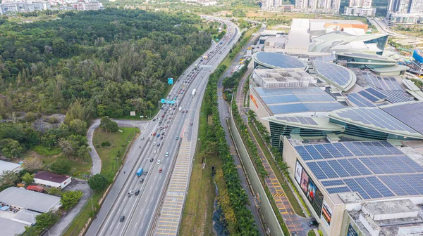 stock image Malaysia- October 13, 2022: Aerial view directly above a highway. Top view of asphalt road passes Shopping mall with Solar panel on the roof. Aerial picture. Sedan cars driving by Autobahn highway.