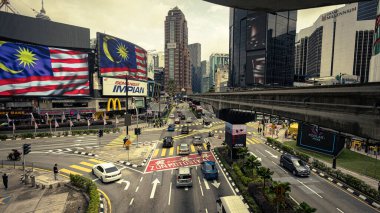 Kuala Lumpur, Malezya - 21 Ağustos 2022: Bukit Bintang kavşağı. KL şehir merkezindeki yoğun kavşağın uzun pozlama görüntüsü. Arabalar ve motorsikletler geçiyor, yukarıdaki raylı haç yolu..
