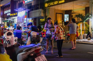 Ho Chi Minh City, Vietnam- 9 Kasım 2022 Saigon 'daki sokak satıcısı mallarını satıyor. Vietnam metropolünün işlek dar sokaklarında gece hayatı. Küçük tezgahlardan popüler sokak yemekleri