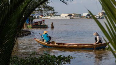 Ho Chi Minh City, Vietnam- 9 Kasım 2022: 2 Vietnamlı kadın, geleneksel konik şapkalı, Mekong nehrinde bir sandalda veya kanoda. Mekong Deltası 'nda tekne gezisi turistik bir eğlencedir.
