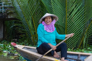 Ho Chi Minh Şehri, Vietnam- 9 Kasım 2022 Mekong deltasındaki sel basmış çivit bitkisi ormanında turizm kayığı. Mekong Delta kürekli tekneleri. Vietnamlı kadın, koni şeklinde bir güneş şapkası, gülüyor.