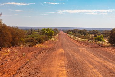 Kings Canyon 'dan Alice Springs' e kadar asfaltsız yol var. Ginty 'nin Gözcüsü yakınlarında. Orta Avustralya 'da binlerce kilometre boyunca çorak bitki örtüsü olan uçsuz bucaksız bir arazi. Kırmızı kum yolu