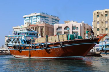 Dubai, UAE - February 14,2022: Dubai Creek with wooden boats floating on the tranquil water under a clear blue sky. Tranquil scene conveys a sense of calm in front of the big city skyline of Dubai