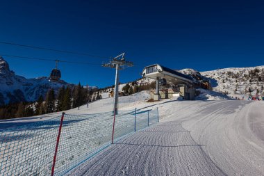 Dolomitler 'deki kar kaplı dağın nefes kesici manzarası, bir de teleferik. Uzaktaki görkemli zirveler karla örtülmüş. Zirveye doğru yükselir, ilham verici bir manzara sağlar.
