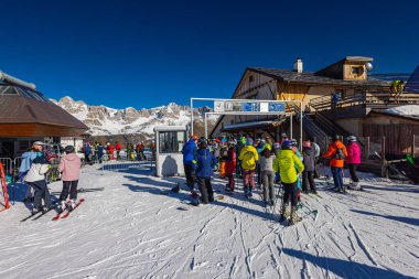Falcade, İtalya - 15 Şubat 2023 Dolomitlerin dağlarındaki bir asansör istasyonunda. Kayakçılar teleferiği almak için sırada bekliyorlar. Kayakçı kuyruğu kayak merkezindeki asansöre kadar, bir sürü insan.