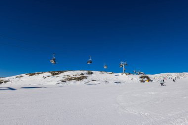 Dolomitler 'deki kar kaplı dağın nefes kesici manzarası, bir de teleferik. Uzaktaki görkemli zirveler karla örtülmüş. Zirveye doğru yükselir, ilham verici bir manzara sağlar.