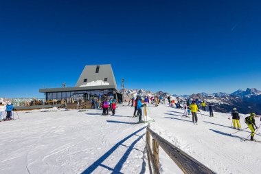 Falcade, İtalya - 15 Şubat 2023 Dolomitlerin dağlarındaki bir asansör istasyonunda. Kayakçılar teleferiği almak için sırada bekliyorlar. Kayakçı kuyruğu kayak merkezindeki asansöre kadar, bir sürü insan.
