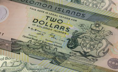 Solomon Adaları 'nın 2 dolarlık banknotunda karmaşık sanat eserleri ve tasarımlar yer almaktadır. Yakın plan, canlı renkleri, yerel motifleri ve önde gelen bir tarihsel figürün portresini, para sanatını gözler önüne serer.