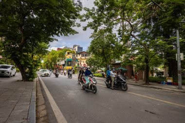 Hanoi, Vietnam - 28 Mayıs 2023: Büyüleyici Eski şehir sokakları canlı bir tablo ortaya koyuyor: motorlar ve bisikletler hızla geçiyor, melodik bir kakofoni yaratıyorlar. Bu enerjik sahne Vietnam kültürünü gözler önüne seriyor
