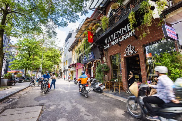 Hanoi, Vietnam - 28 Mayıs 2023: Büyüleyici Eski şehir sokakları canlı bir tablo ortaya koyuyor: motorlar ve bisikletler hızla geçiyor, melodik bir kakofoni yaratıyorlar. Bu enerjik sahne Vietnam kültürünü gözler önüne seriyor