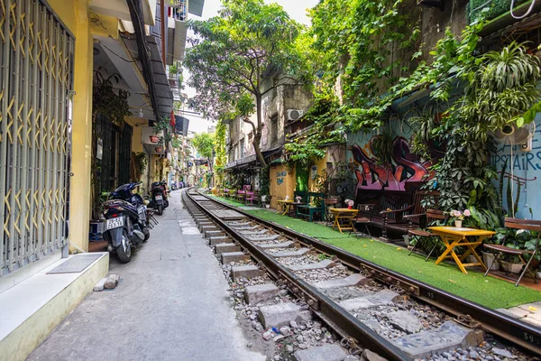 Hanoi, Vietnam - 28 Mayıs 2023 Hanoi 'deki tren yolu dar ve hareketli bir şerit. Bitkilerle süslenmiş birbirine yakın evler, geçen trenlerden birkaç santim uzaklıktadır. barlar ve kafeler rayları çiziyor