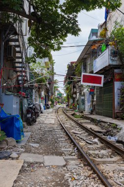 Hanoi, Vietnam - 28 Mayıs 2023 Hanoi 'deki tren yolu dar ve hareketli bir şerit. Bitkilerle süslenmiş birbirine yakın evler, geçen trenlerden birkaç santim uzaklıktadır. barlar ve kafeler rayları çiziyor