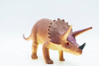 Triceratops dinozor oyuncağı, beyaz arka planda kırmızı gözlü.