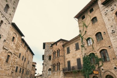 Tırmanma tesisi olan antik binalar ve San Gimignano, Toskana, İtalya 'nın solmuş gökyüzü..