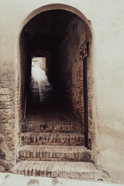 Ortaçağ 'ın San Gimignano kasabasındaki taş bir kapının altındaki merdivenler. Toskana, kuzey-orta İtalya. Güzel Kuleler Kasabası olarak bilinir..