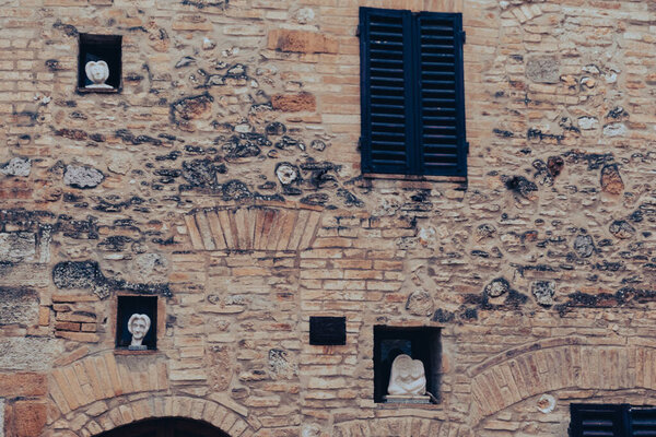 Ancient brick wall with statues on the facade at San Gimignano, in the province of Siena, Tuscany, north-central Italy.