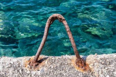 İskelede kristal mavi suyla paslı metal kanca