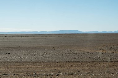 A winding road through the vast Sahara desert of Morocco, with golden sand dunes stretching as far as the eye can see