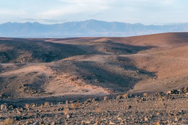 Stunning view of black and red rocky mountains with a river on the bottom at sunset in the sahara desert in morocco