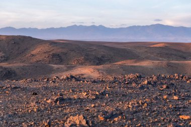 Stunning view of black and red rocky mountains with a river on the bottom at sunset in the sahara desert in morocco