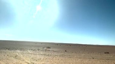 The vast, barren landscape of the Sahara desert seen from inside the car on a road trip through Morocco