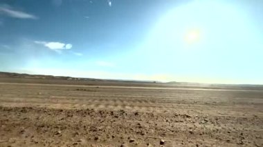 The vast, barren landscape of the Sahara desert seen from inside the car on a road trip through Morocco