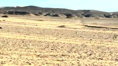The vast, barren landscape of the Sahara desert seen from inside the car on a road trip through Morocco
