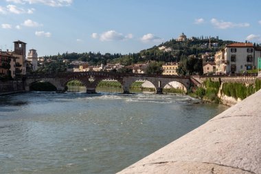 View of a medieval bridge over the Adige river in Verona from a low wall. Sunny day. Italy.