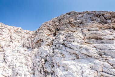 Irregular rock face with blue sky in the background on a beautiful warm sunny day in Santoniri, Greece.