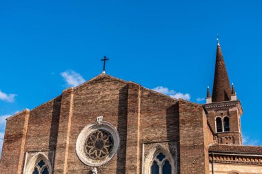 Medieval brick church with pointed roof bell tower on a blue sky day in Verona. Italy.