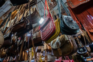 Bags of leather and colorful fabrics hanging in a shop in a souk in Marrakech. Morocco