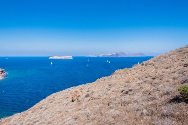 View of the sea and islands with sailboats on a summers day and blue sky in Santorini Greece