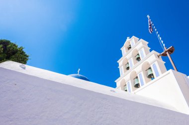 Beyaz ve açık mavi çan kulesi Santorini 'de Yunan bayraklı bir kilisenin.