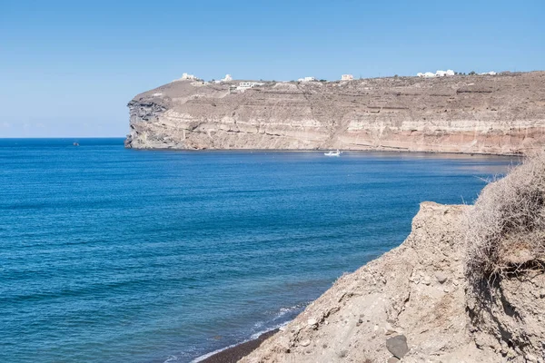 サントリーニ島の穏やかな海と背景にギリシャの島の岩壁と小さなボート 夏の目的地 — ストック写真