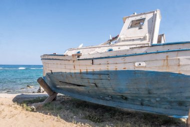Bu yıpranmış ve terk edilmiş eski tekne, zamanın akışının ve içinde barındırdığı hikayelerin bir kanıtı olarak sessizce kıyıda duruyor..