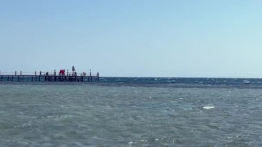 İskelenin Ortası Güçlü Akıntılar: Mısır 'da Kızıldeniz Güzelliği. Yüksek kalite 4K görüntü. Bu büyüleyici görüntü, güçlü ve sığ akıntılar arasında bir iskeleyi çevreleyen Kızıl Deniz cazibesini yakalar. Tecrübe