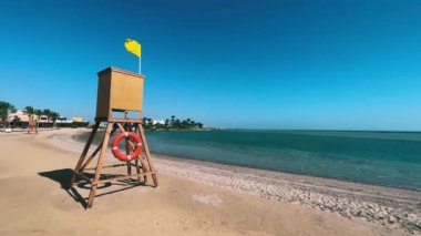 Sarı Bayrak 'lı Güçlü Rüzgarlar Arasındaki Mısır Cankurtaran Kulesi. Yüksek kalite 4K görüntü. Hurghada. El Gouna 'da. Cankurtaran kulesi dimdik dururken Mısır 'ın kıyı güzelliğinin canlı özünü yakalayın.