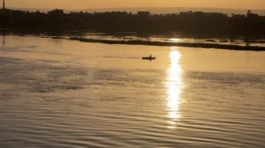 Altın Nil Serenity: Sunset 'te balıkçı. Yüksek kalite 4K görüntü. Nil Nehri 'nin sakin güzelliğini gün batımında yakalayın. Orada yalnız bir balıkçı huzur içinde altın sularda süzülür. Bu huzur