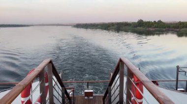 Nil Nehri Mirası: Ebedi Sularda Gemi Uyanışı. Yüksek kalite 4K görüntü. Zarif uyanışı Nil 'in ebedi sularında yol alırken bir yolcu gemisinin ebedi mirasına tanık olun.