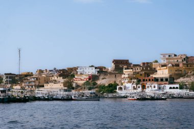 Nil Nehri 'nin ebedi güzelliğine karşı küçük bir limanın kayıklarla dolu olduğu Mısır nehir kıyısındaki bir kasabanın dinginliğini kucaklayın. Bu fotoğraf, Mısır 'ın köylerinin kalbini tanımlayan sükunet cazibesini özetliyor. Bunu iletmek için kullan.