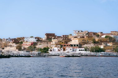 Nil Nehri 'nin ebedi güzelliğine karşı küçük bir limanın kayıklarla dolu olduğu Mısır nehir kıyısındaki bir kasabanın dinginliğini kucaklayın. Bu fotoğraf, Mısır 'ın köylerinin kalbini tanımlayan sükunet cazibesini özetliyor. Bunu iletmek için kullan.